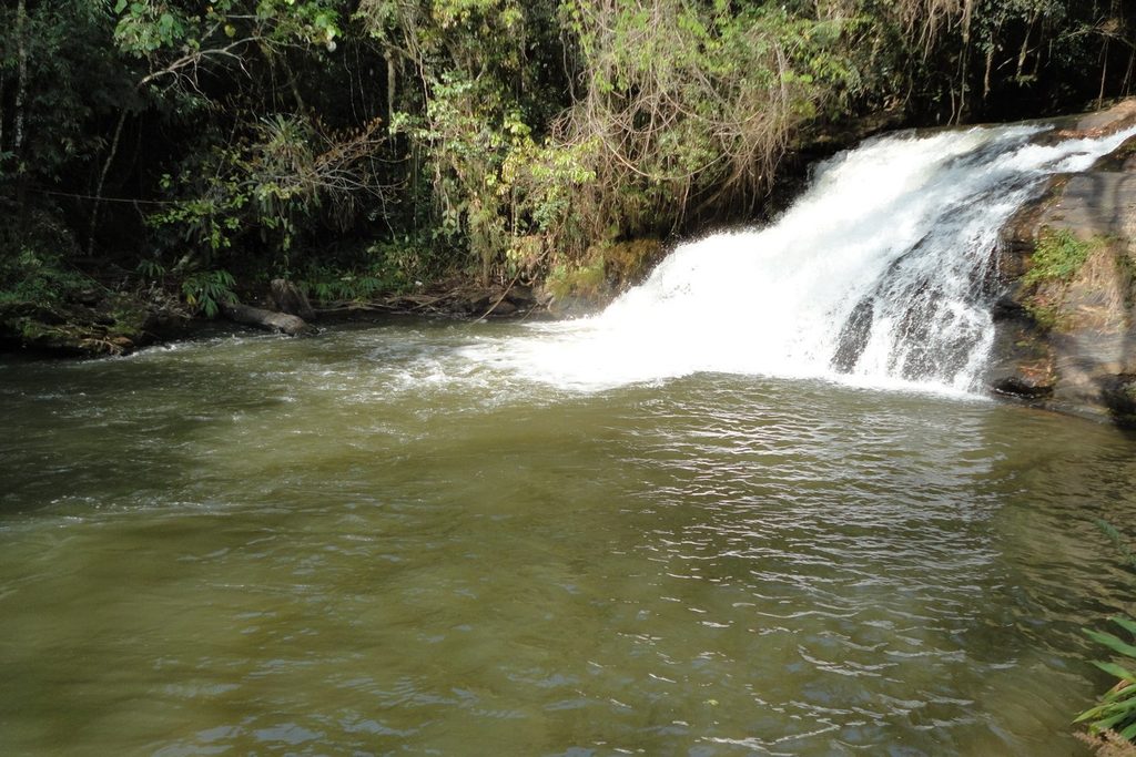 Cachoeira do Pião, em Piracaia, caindo entre pedras num poço largo cercado de mata