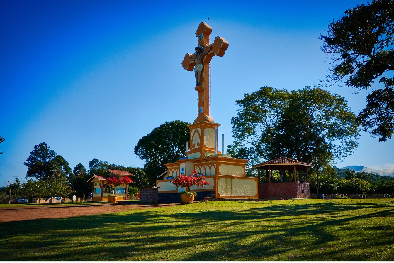 Santo Cruzeiro de Piracaia, cruz alta de 14 metros com Cristo crucificado, sobre base de concreto num gramado sob céu azul