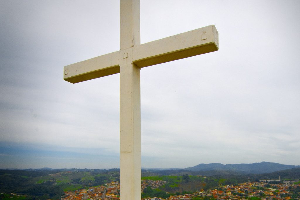 Cruzeiro branco no alto do morro com a vista da cidade e das serras ao fundo