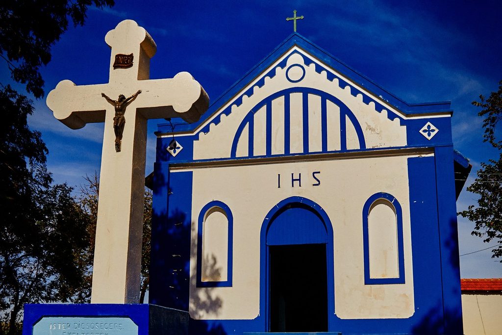 Capela branca e azul de Santo Estevão, com cruzeiro ao lado, na Colônia Árpádfalva