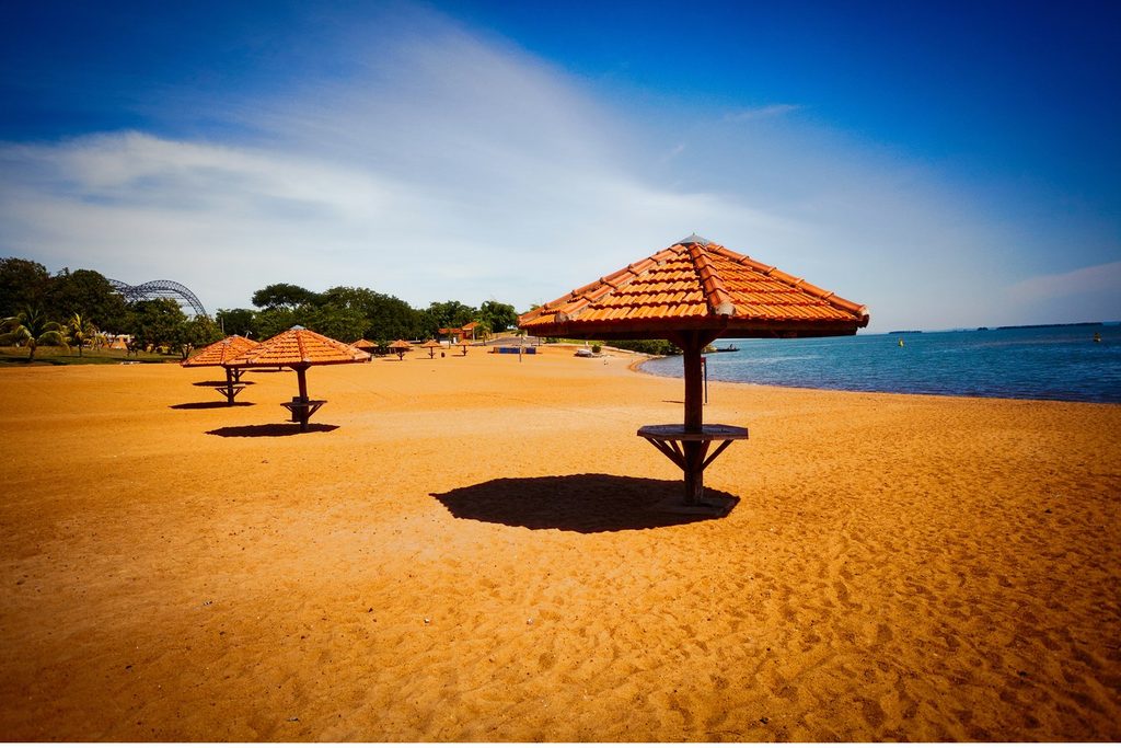 Praia de areia com quiosques de telhado de barro na beira do Rio Paraná, no Balneário O Figueiral