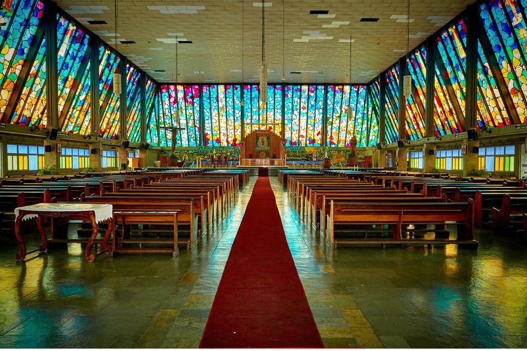 Interior da Sé Catedral de São José, em São José do Rio Preto, com paredes de vitrais coloridos e tapete vermelho no corredor central