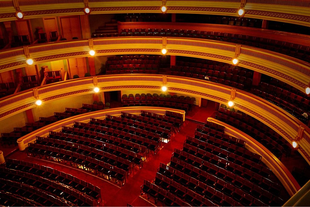 Plateia e camarotes do Theatro Pedro II, em Ribeirão Preto, com fileiras de poltronas vermelhas e balcões curvos iluminados