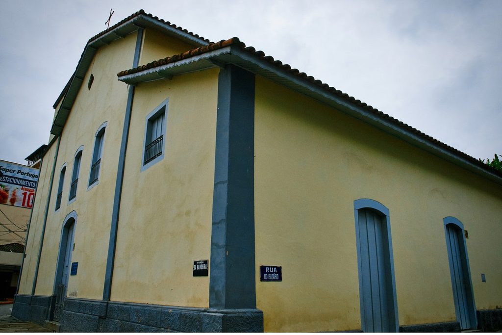 Fachada lateral da Igreja do Rosário, em Santa Isabel, de paredes amarelas e portas azuis, construída em taipa de pilão