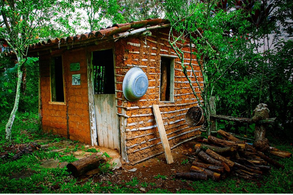 Casa de pau a pique com telhado de barro e lenha empilhada no Museu da Casa Rural, em Santa Isabel