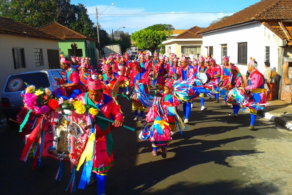 Grupo de congada com roupas coloridas e fitas dançando na rua durante a Festa de Congo de Santo Antônio da Alegria