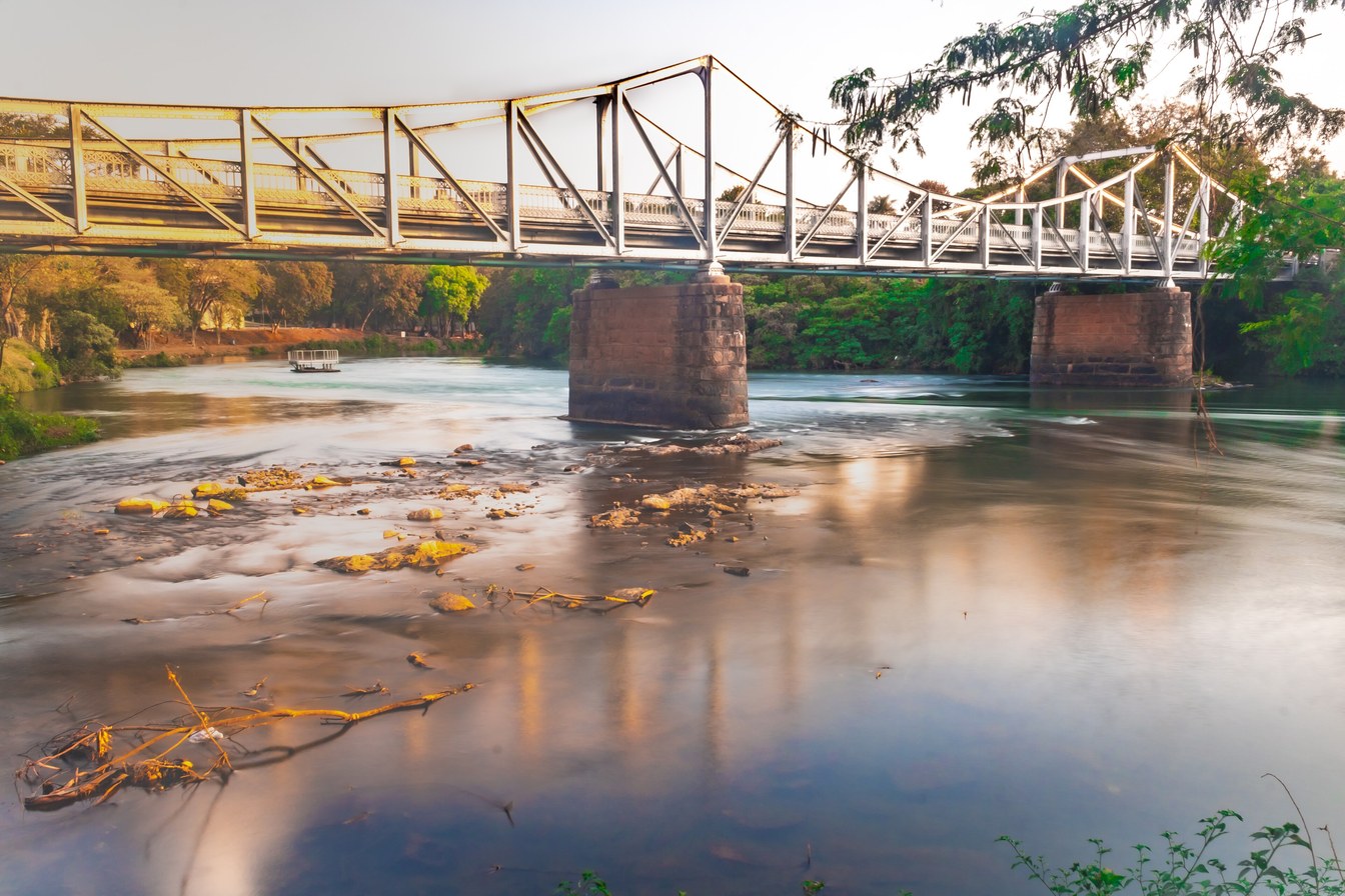 Ponte metálica Euclides da Cunha sobre o Rio Pardo, em São José do Rio Pardo, refletida na água na luz dourada do fim da tarde