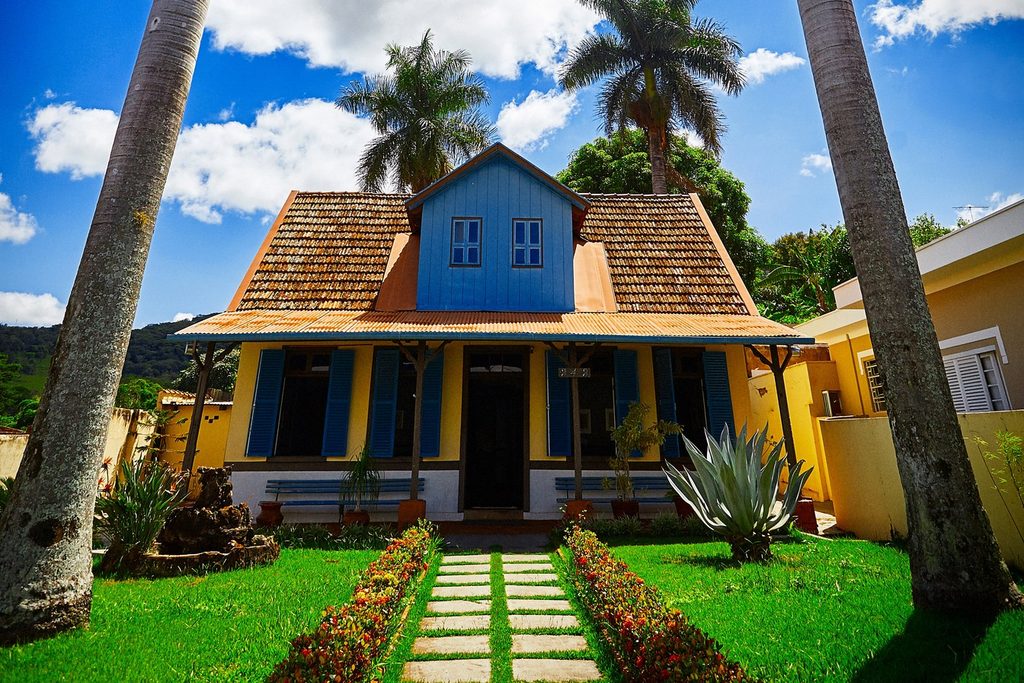 Chalé alemão azul e amarelo da Casa da Cultura Marcelo Grassmann, entre palmeiras, em São Simão SP