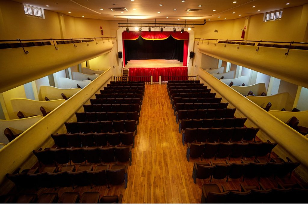 Plateia, camarotes laterais e palco com cortina vermelha do Teatro Carlos Gomes