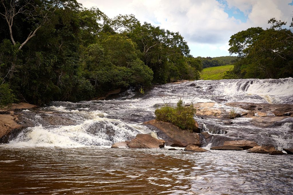 Rio Paraitinga descendo em corredeiras largas sobre pedras, entre a mata, na Cachoeira do Paraitinga, em Silveiras