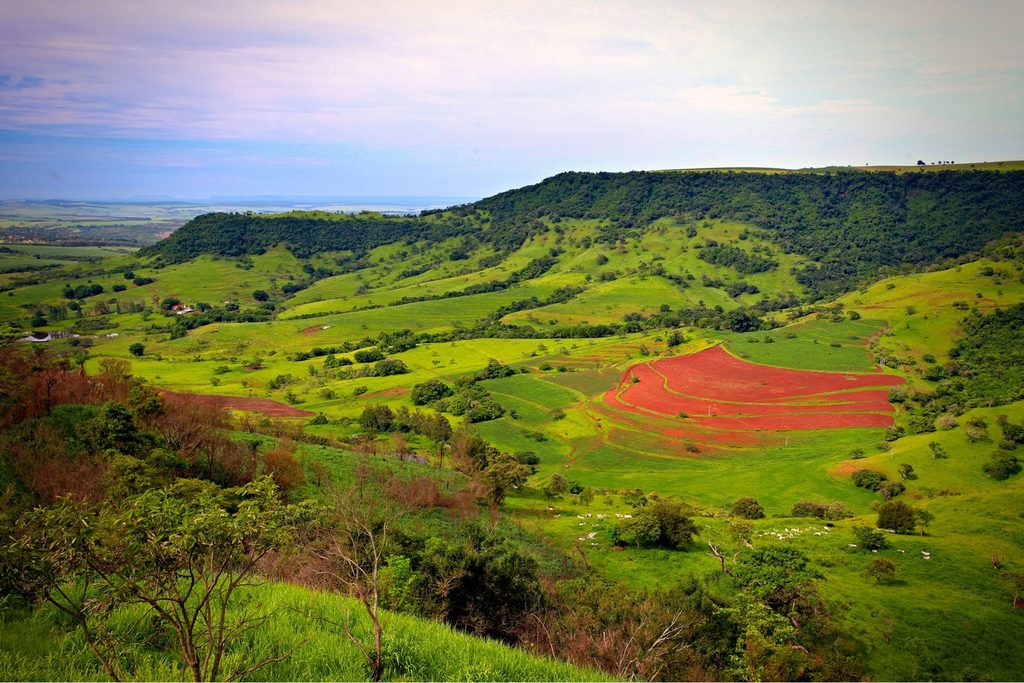 Vista do alto da Serra do Itaqueri em São Pedro, com vale verde, plantações e paredão de morro coberto de mata