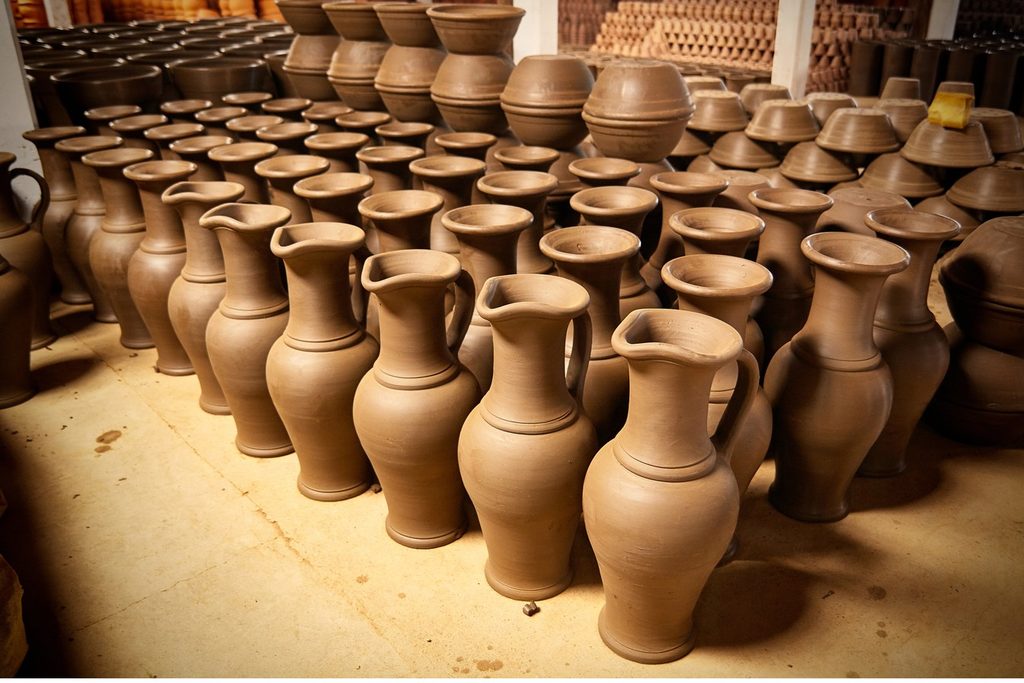 Dezenas de jarras e vasos de argila crua secando lado a lado numa fábrica de cerâmica