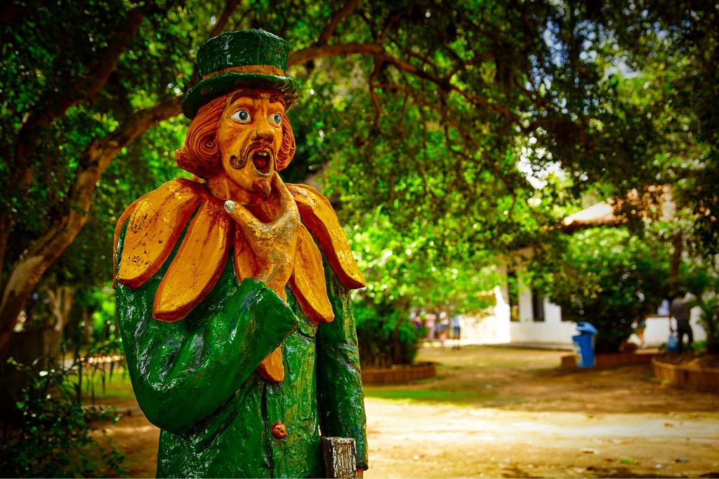 Estátua colorida do Visconde de Sabugosa, de cartola e casaca verde, no jardim arborizado do Sítio do Picapau Amarelo, em Taubaté