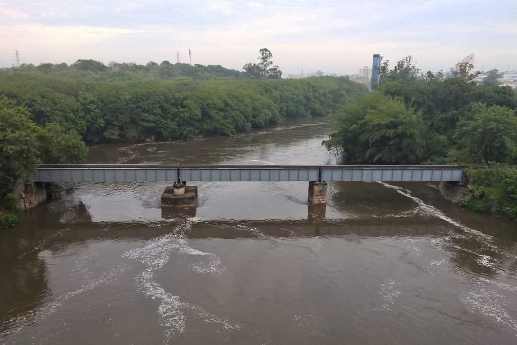 Antiga ponte ferroviária de metal atravessando o rio Tietê, com mata nas margens, em Salto