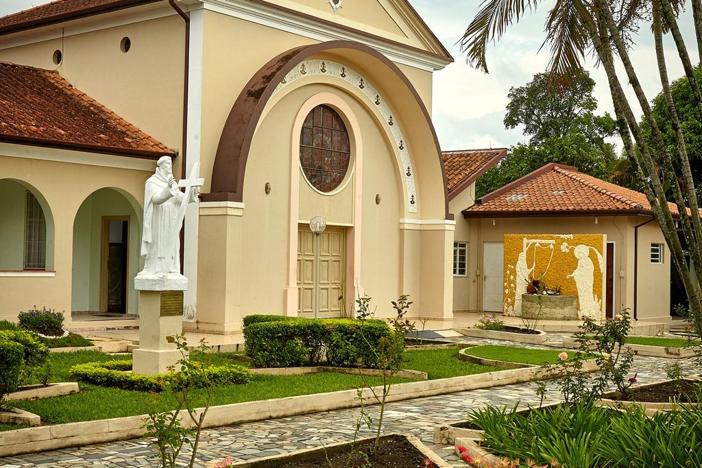 Capela clara do Carmelo Santa Face e Pio XII, com arco, janela redonda, estátua branca e jardim na frente